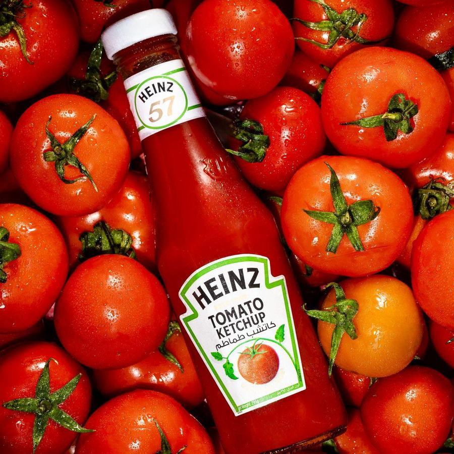 A ketchup bottle lying in a bed of ripe tomatoes, photographed from overhead