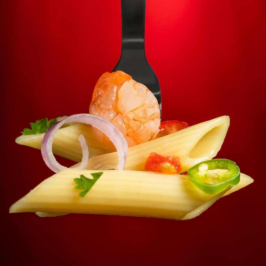 Penne pasta and a prawn balanced on a fork against a vivid red background