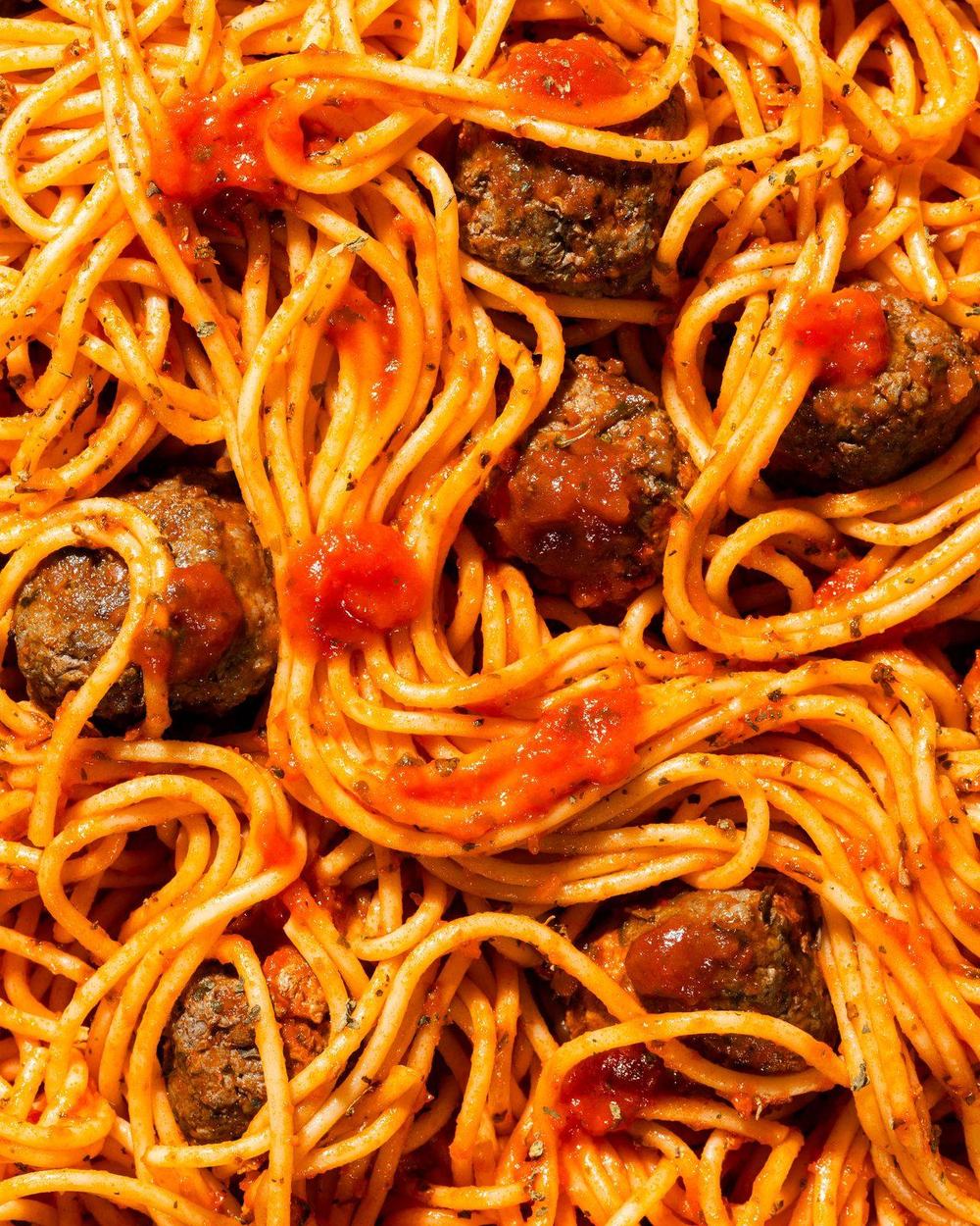 Spaghetti and meatballs in tomato sauce, filling the frame, lit to bring out the texture of the sauce